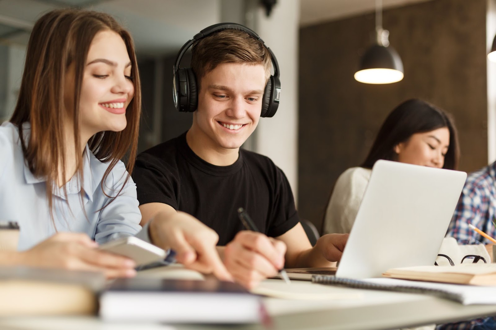 Jovens fazendo anotações no papel e mexendo no computador 