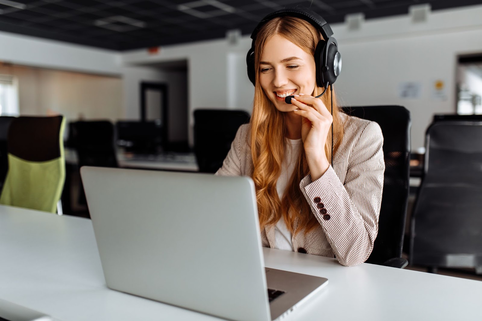 Mulher mexendo no computador e falando pelo microfone em atendimento ao cliente