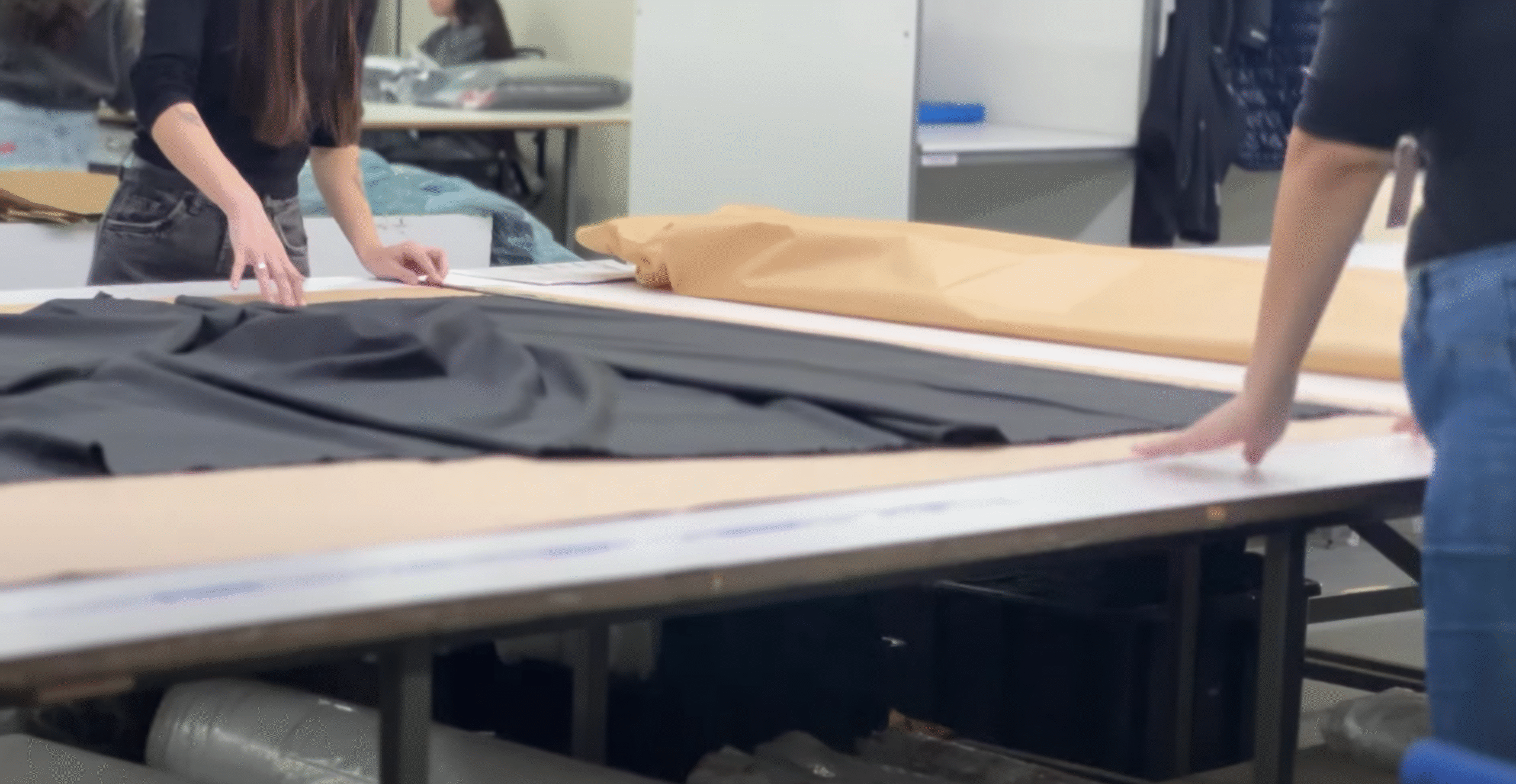 Mesa de corte com mulheres organizando o enfesto de tecido