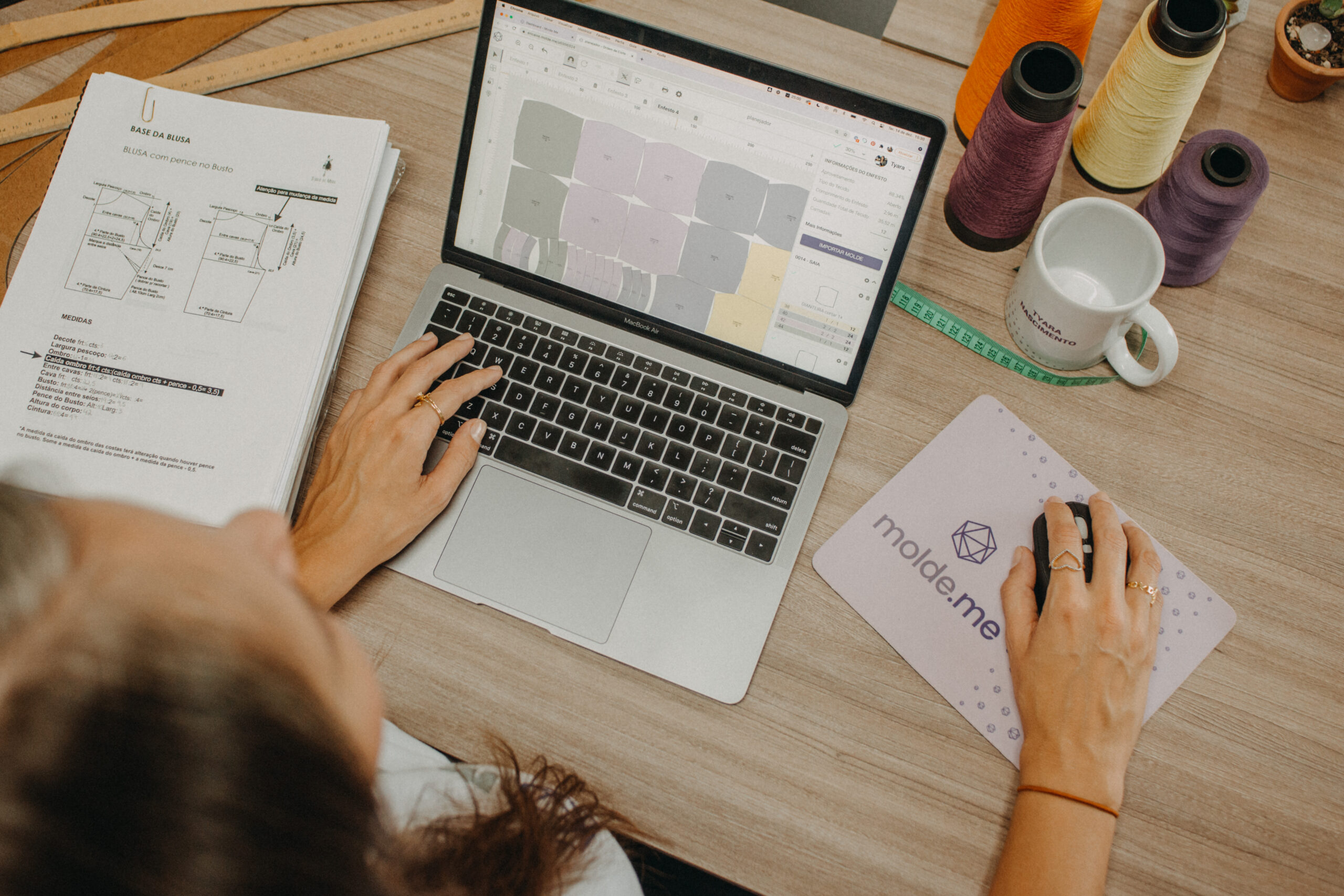 Mulher mexendo em computador que está apoiado sobre a mesa, na tela aparece a interface do sistema Molde.me
